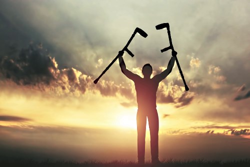 silhouette of man with crutches over his head